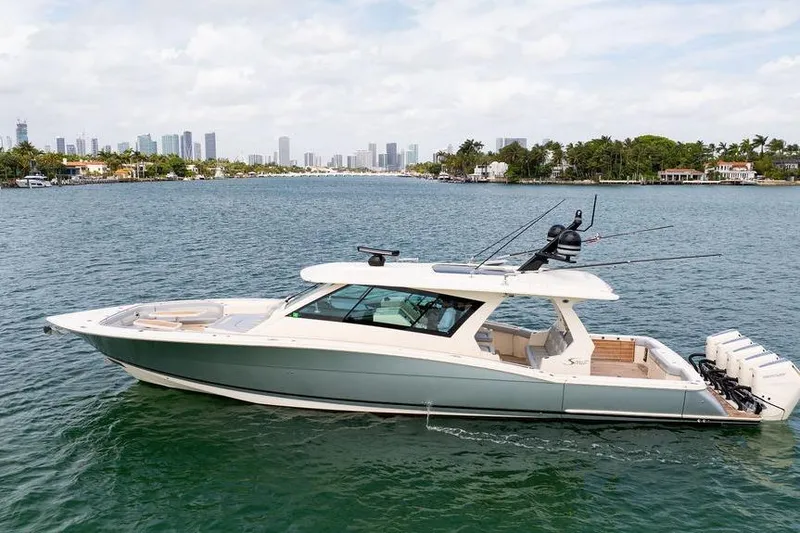 Slide: The Image of 2020 Scout 530 LXF luxury boat cruising on a scenic waterway with city skyline. - 16