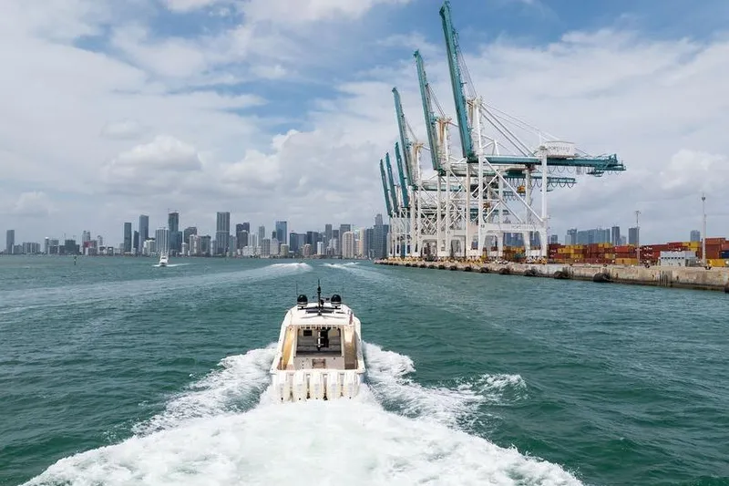 Slide: The Image of 2020 Scout 530 LXF boat cruising near port cranes and city skyline. - 30