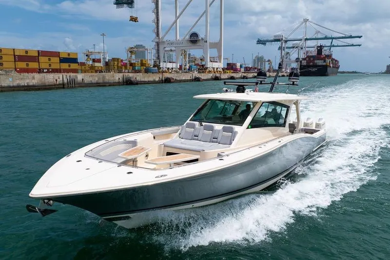 Slide: The Image of 2020 Scout 530 LXF luxury boat cruising near a busy port with shipping containers. - 33