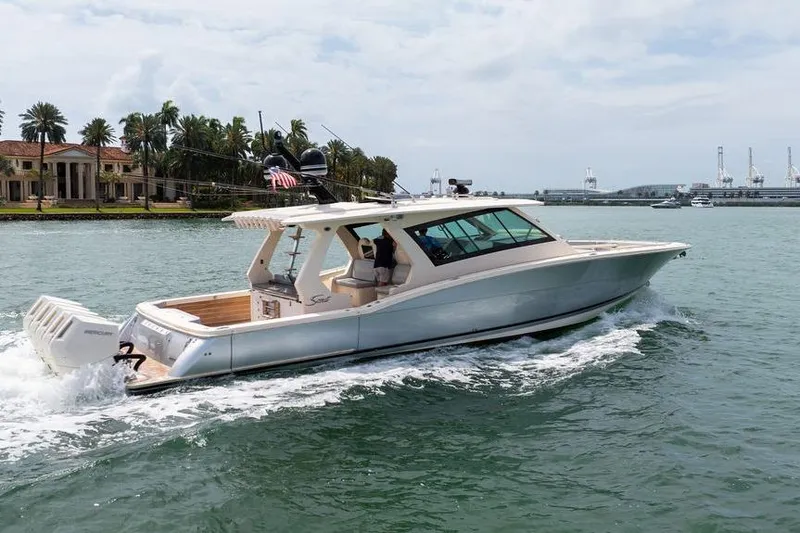 Slide: The Image of 2020 Scout 530 LXF luxury boat cruising near waterfront estate. - 8