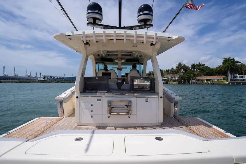 Slide: The Image of 2020 Scout 530 LXF luxury boat on water, rear view with open deck and clear sky. - 85