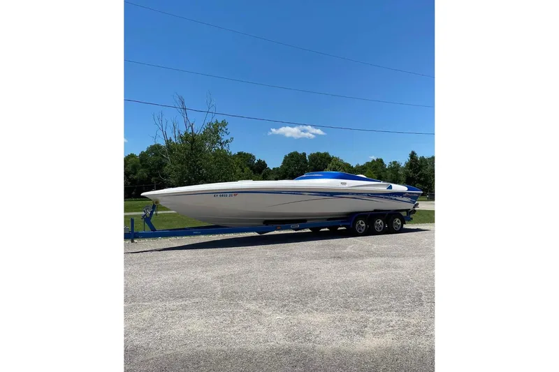 The Image of 2004 Sunsation 32 Dominator speedboat on trailer, parked outdoors under clear blue sky. - 1