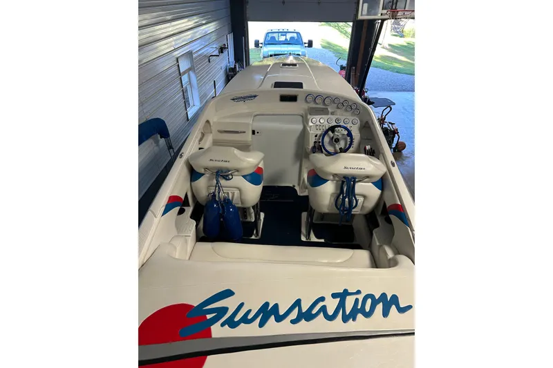 Slide: The Image of 2004 Sunsation 32 Dominator boat interior with branded seating and dashboard in a garage. - 20