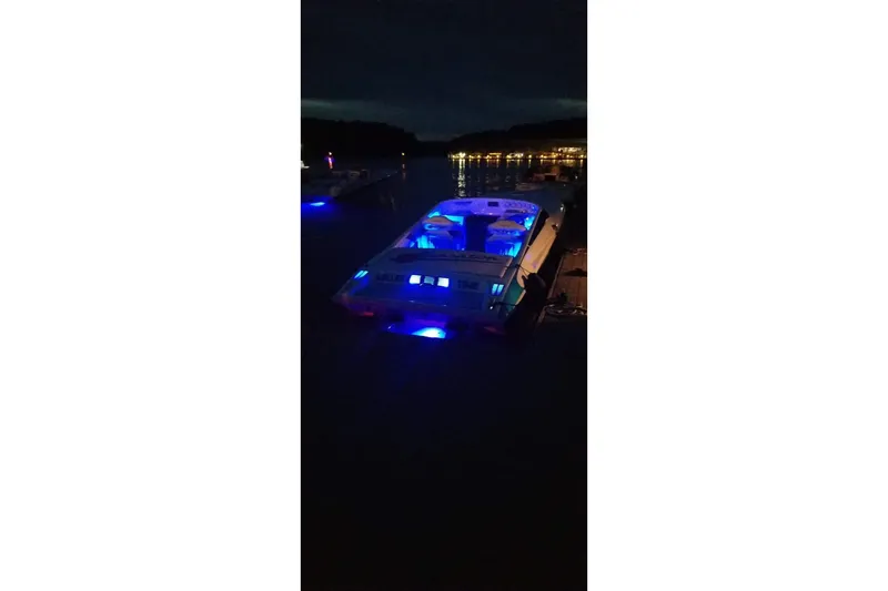 Slide: The Image of 2004 Sunsation 32 Dominator boat illuminated with blue lights at night on the water. - 34