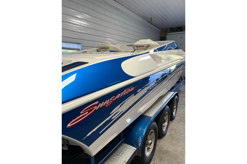 Slide: The Image of 2004 Sunsation 32 Dominator boat in garage, blue and white design on trailer. - 8