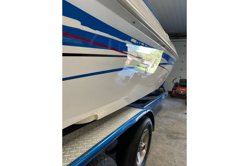Slide: The Image of 2004 Sunsation 32 Dominator boat with blue and red stripes on a trailer in a garage. - 9