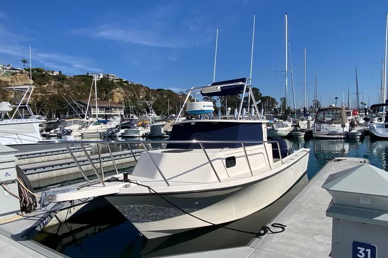 The Image of 2006 Parker 2520 SL Sport Cabin boat docked in a marina under clear blue skies. - 0