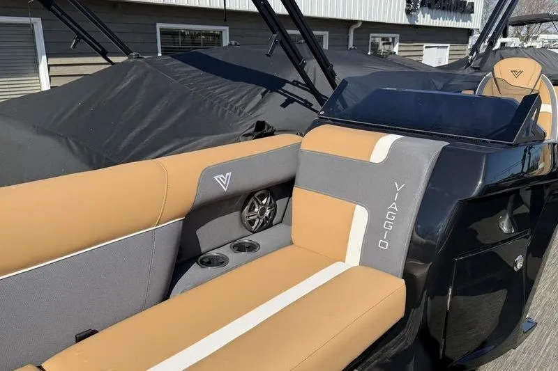 Slide: The Image of 2026 Viaggio x22u boat interior with tan and gray seating, featuring cup holders and speaker. - 12