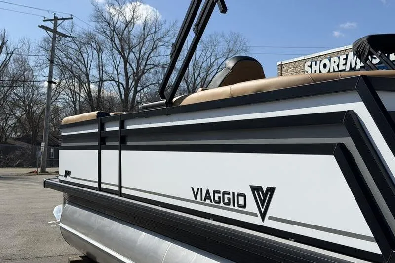 Slide: The Image of 2026 Viaggio x22u pontoon boat with sleek design and branding, parked outdoors. - 2