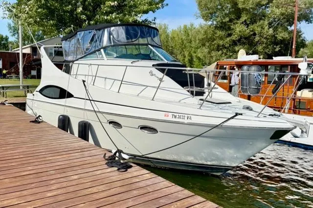 Slide: The Image of 1998 Carver 350 Mariner yacht docked at a marina, surrounded by trees and water. - 4