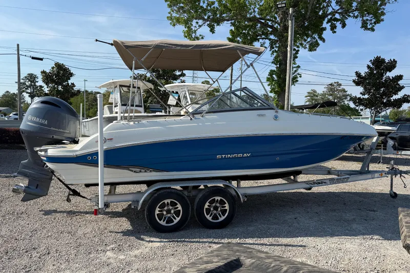 Slide: The Image of 2019 Stingray 201 DS boat on trailer with Yamaha outboard motor, parked outdoors. - 10