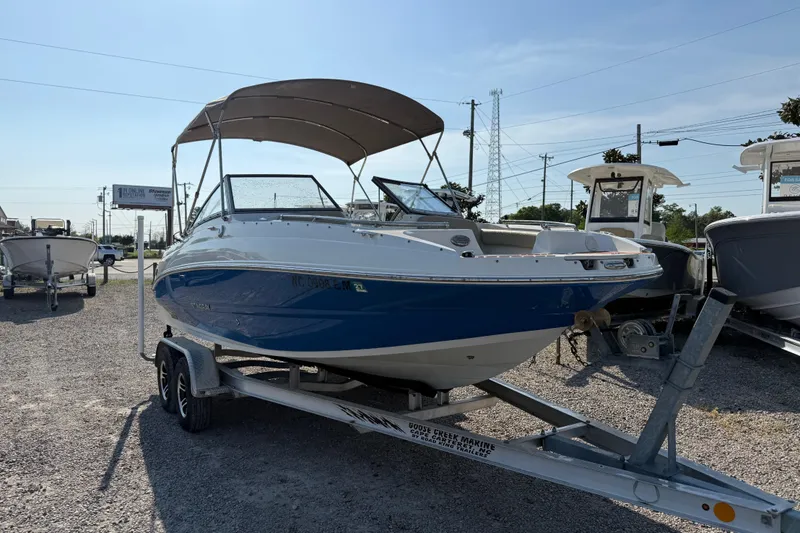 Slide: The Image of 2019 Stingray 201 DS boat on trailer, blue and white, with canopy, parked outdoors. - 12