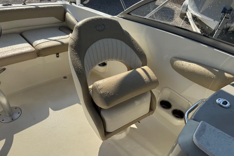 Slide: The Image of 2019 Stingray 201 DS boat interior with beige seating and cup holders. - 21