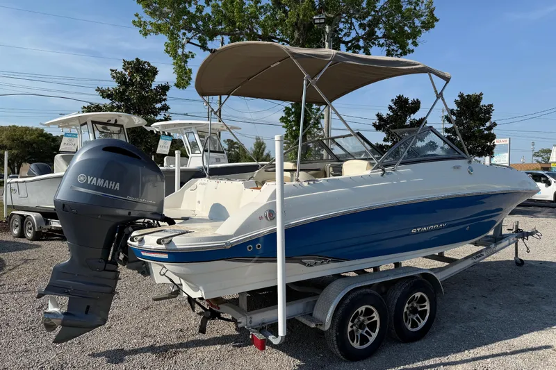 Slide: The Image of 2019 Stingray 201 DS boat with Yamaha outboard motor on a trailer, parked outdoors. - 9