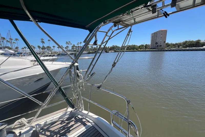 Slide: The Image of Sailboat deck view of 2001 Beneteau Oceanis 473, featuring steering wheel and marina backdrop. - 45