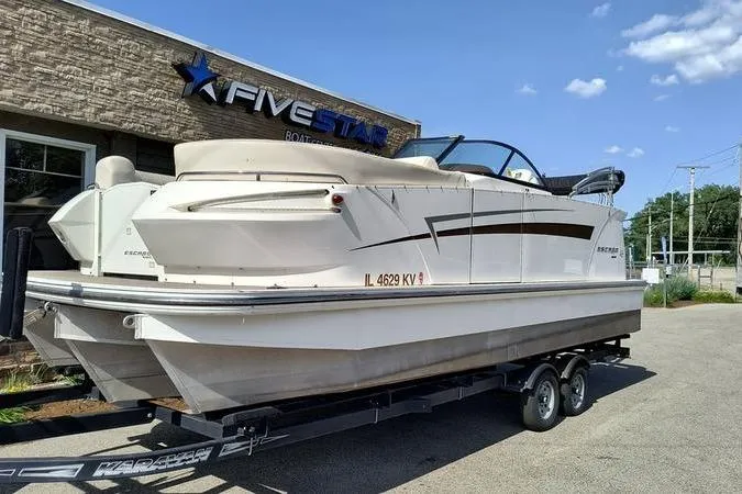 The Image of 2017 Larson Escape 213 boat on trailer outside dealership under clear sky. - 0