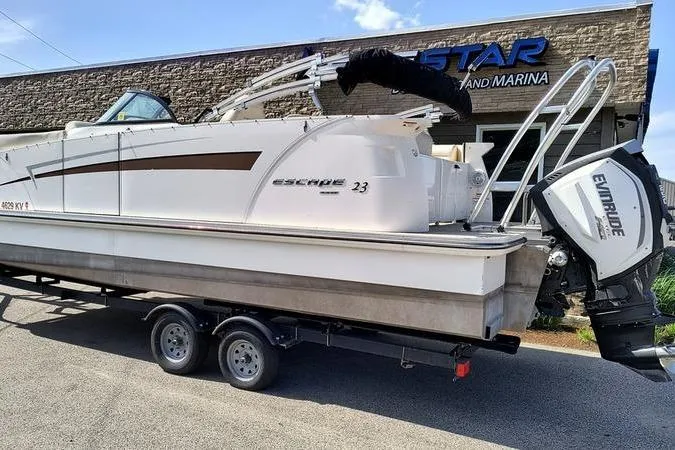 Slide: The Image of 2017 Larson Escape 213 boat on trailer outside a marina, featuring Evinrude engine. - 3
