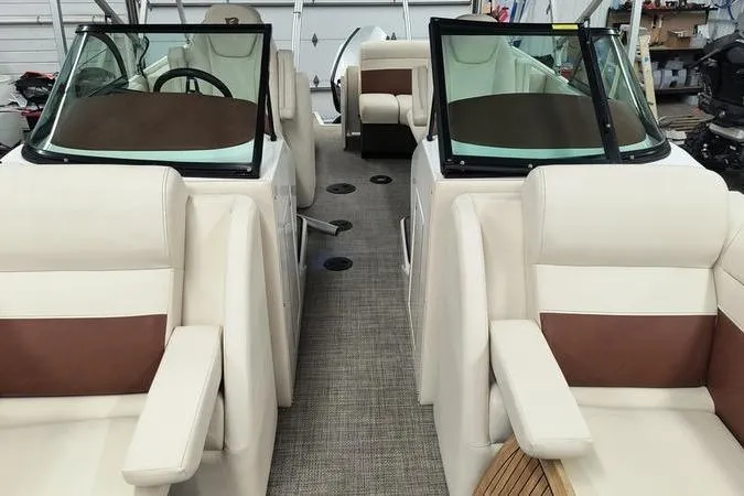 Slide: The Image of 2017 Larson Escape 213 boat interior with beige and brown seating, dual consoles, and steering wheel. - 7