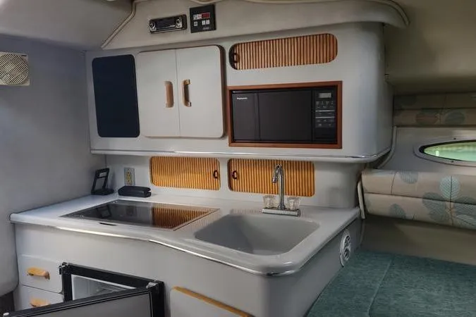 Slide: The Image of 1991 Sea Ray 280 Weekender interior kitchen with sink, stove, and microwave. - 14