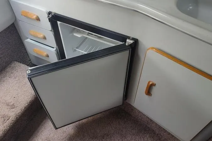 Slide: The Image of 1991 Sea Ray 280 Weekender interior with open mini fridge and storage cabinets. - 17