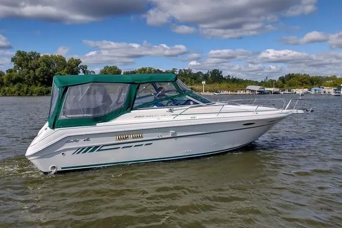 Slide: The Image of 1991 Sea Ray 280 Weekender boat on a calm lake under a partly cloudy sky. - 2