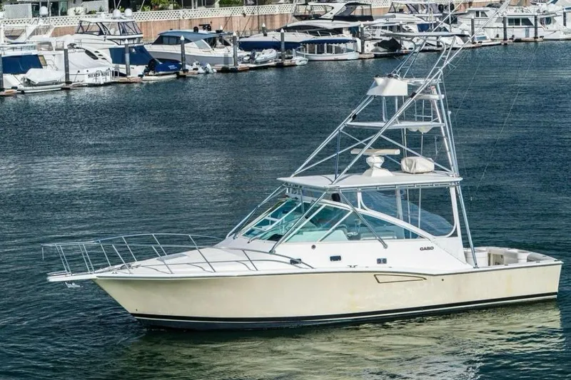 The Image of 1998 Cabo Yachts 35 Express boat docked in a marina, surrounded by other vessels. - 0