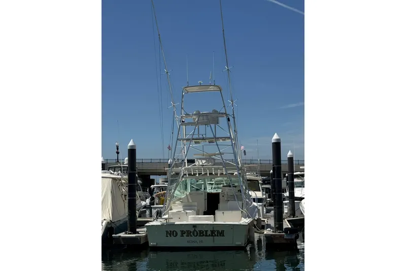 Slide: The Image of 1998 Cabo Yachts 35 Express docked at marina, clear sky background. - 14
