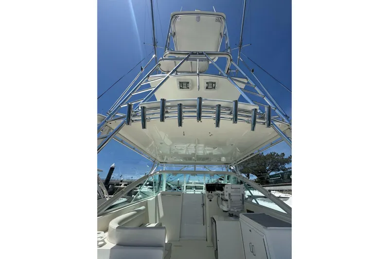 Slide: The Image of 1998 Cabo Yachts 35 Express boat with tower and fishing rod holders under clear blue sky. - 16