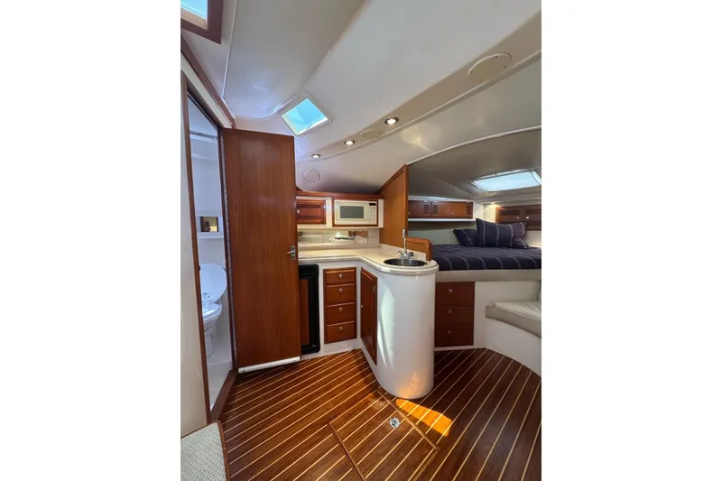 Slide: The Image of Interior of 1998 Cabo Yachts 35 Express, featuring wood flooring, kitchenette, and cozy sleeping area. - 32