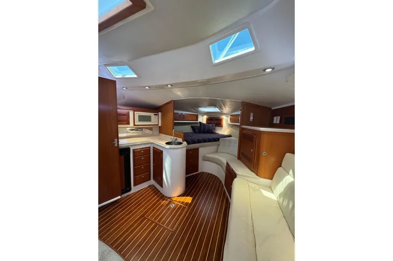 Slide: The Image of Interior of 1998 Cabo Yachts 35 Express, featuring kitchen, seating, and wood flooring. - 37