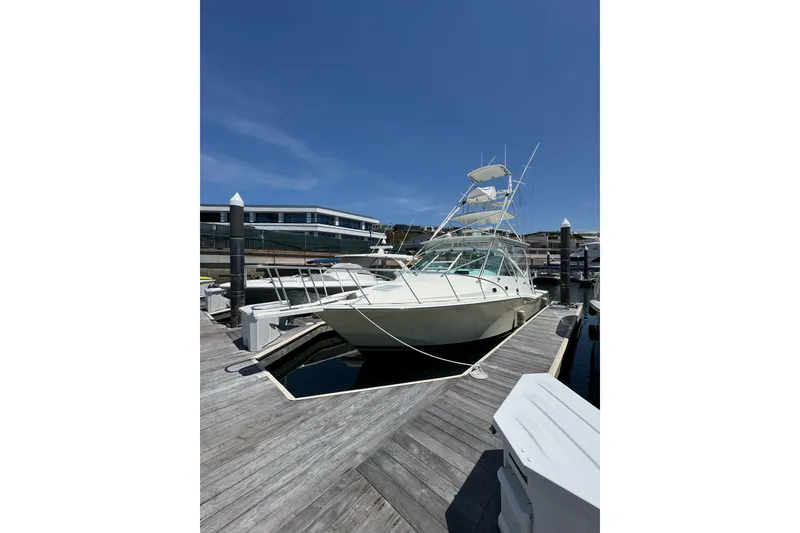Slide: The Image of 1998 Cabo Yachts 35 Express docked at marina under clear blue sky. - 4