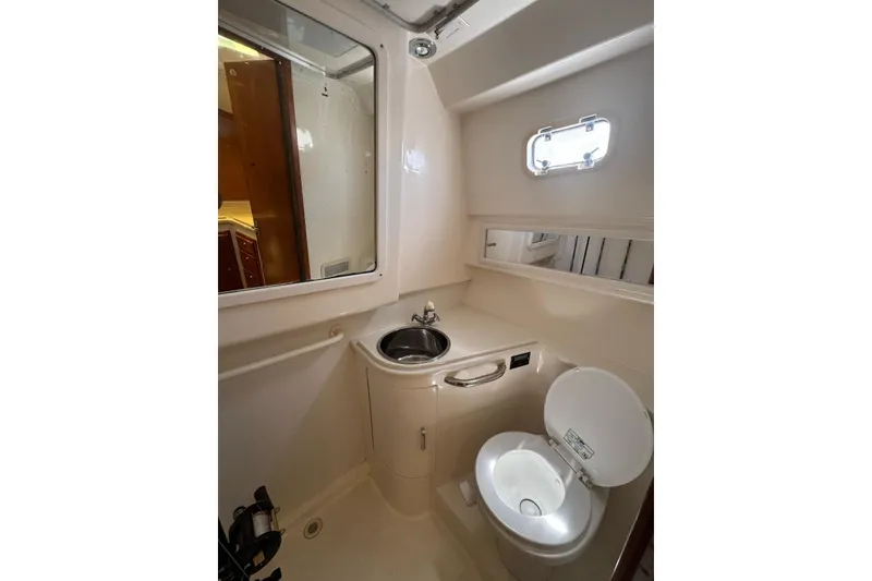 Slide: The Image of 1998 Cabo Yachts 35 Express bathroom with sink, toilet, and porthole window. - 42