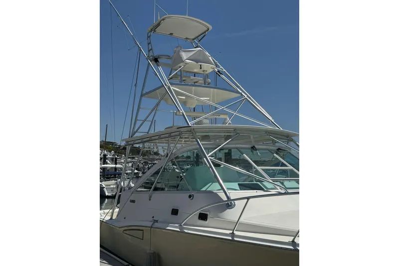 Slide: The Image of 1998 Cabo Yachts 35 Express with tower, docked at marina under clear blue sky. - 6