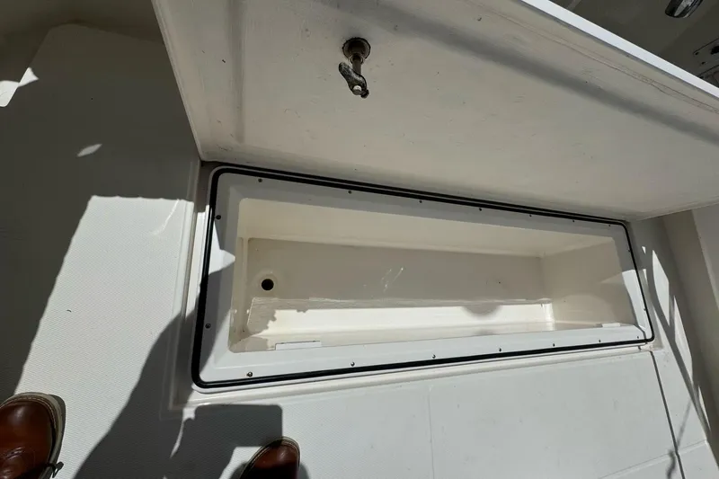 Slide: The Image of 1998 Cabo Yachts 35 Express storage compartment, open and empty, with visible latch and shadow. - 62