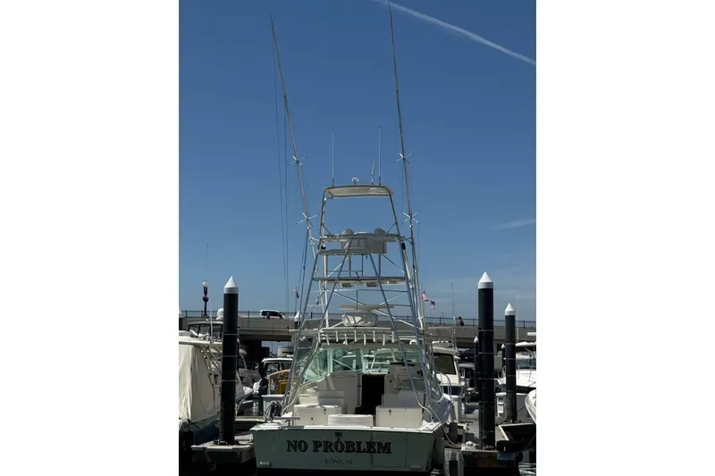 Slide: The Image of 1998 Cabo Yachts 35 Express docked, featuring tall fishing towers under a clear blue sky. - 70