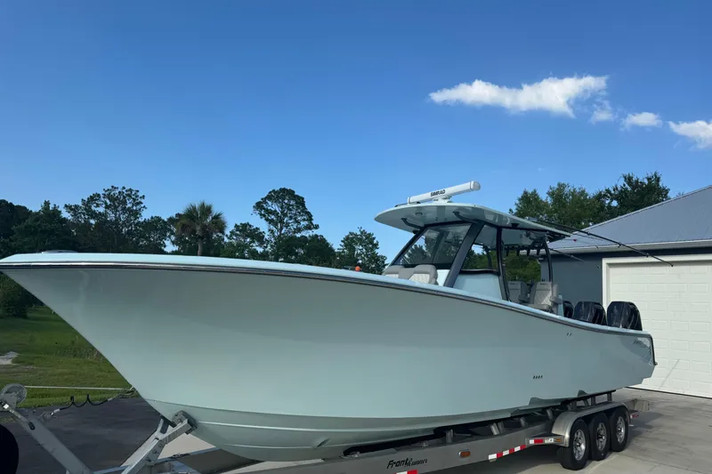 Slide: The Image of 2024 Front Runner boat on trailer, parked outdoors under clear blue sky. - 2