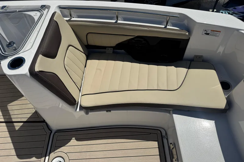 Slide: The Image of 2026 Yamaha Boats 255 FSH Sport E interior seating with beige cushions and cup holder. - 19