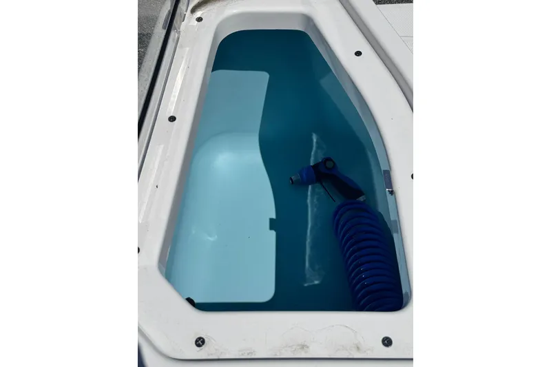 Slide: The Image of Yamaha Boats 2026 255 FSH Sport E storage compartment with blue hose. - 31