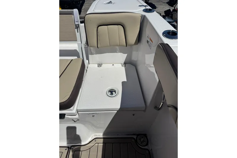 Slide: The Image of 2026 Yamaha Boats 255 FSH Sport E interior seating with beige cushions and cup holders. - 29