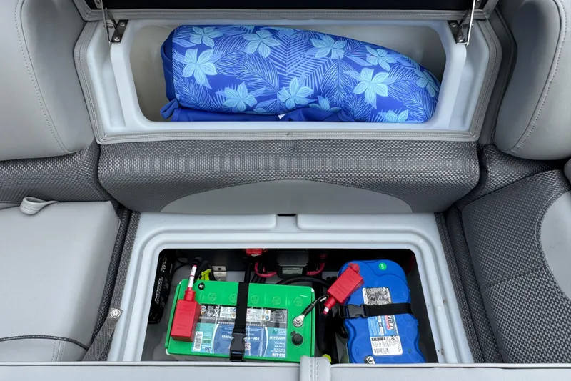 Slide: The Image of Storage compartment in 2024 Regency 230 DL3 with battery and blue floral cushion. - 24