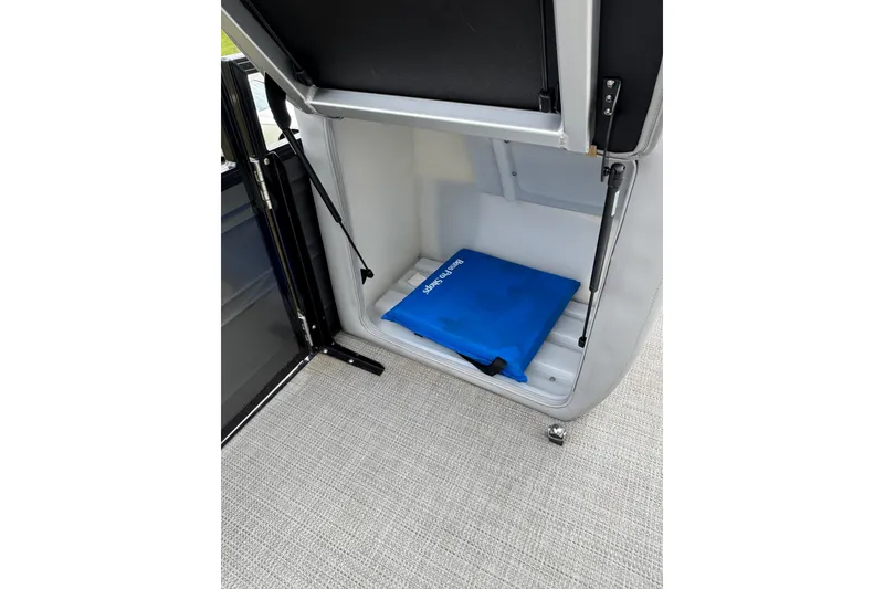 Slide: The Image of Open storage compartment in 2024 Regency 230 DL3 boat with blue cover inside. - 30
