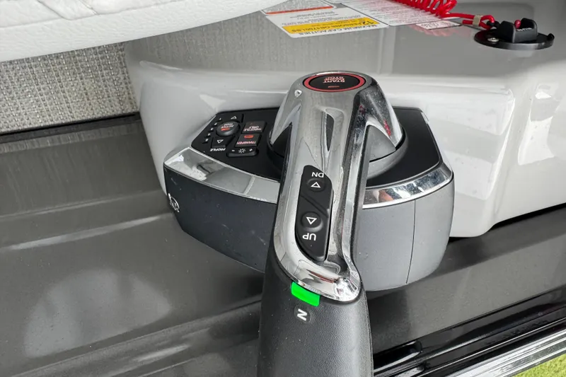 Slide: The Image of Close-up of 2024 Regency 230 DL3 boat throttle control with buttons and safety features. - 32