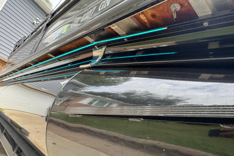 Slide: The Image of 2024 Regency 230 DL3 pontoon boat with sleek reflective exterior and blue accent lighting. - 39