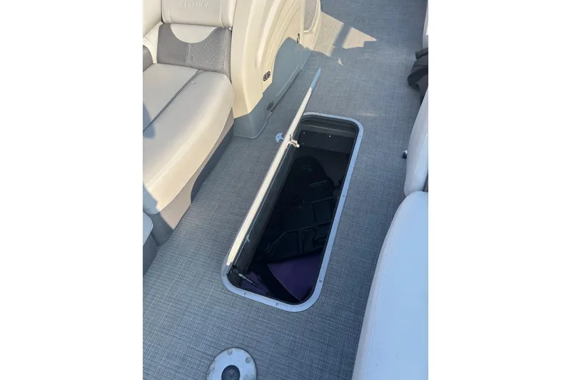 Slide: The Image of 2021 Regency 250 DL3 boat interior with open storage compartment on carpeted floor. - 12