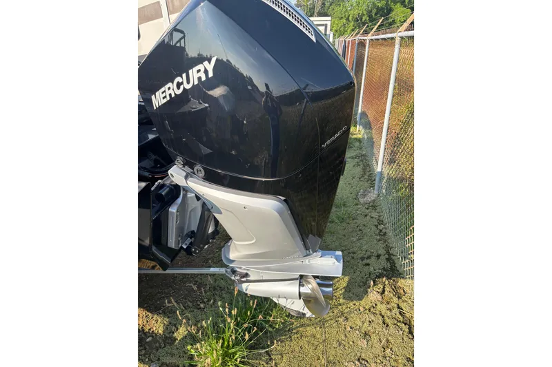 Slide: The Image of 2021 Regency 250 DL3 boat with Mercury outboard motor, parked near a fence. - 21