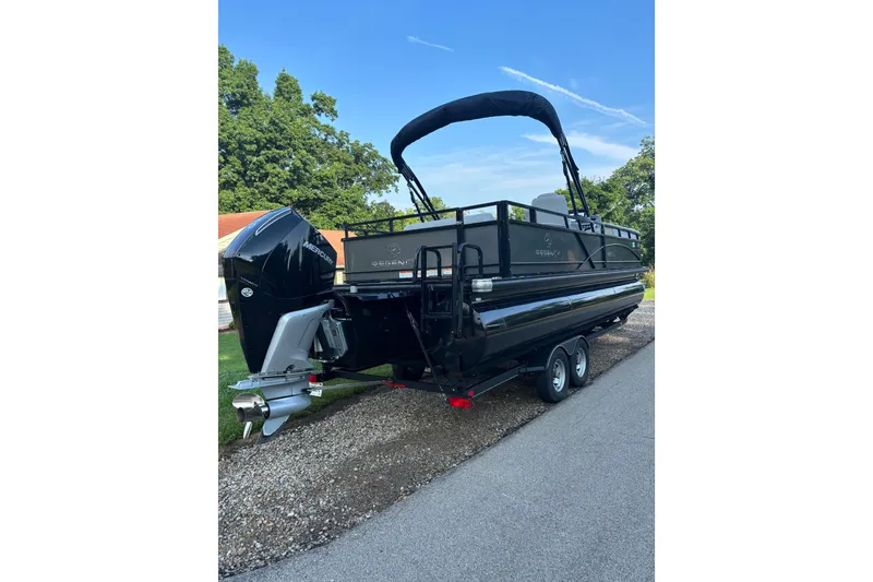 Slide: The Image of 2021 Regency 250 DL3 pontoon boat with Mercury engine on a trailer, parked outdoors. - 3