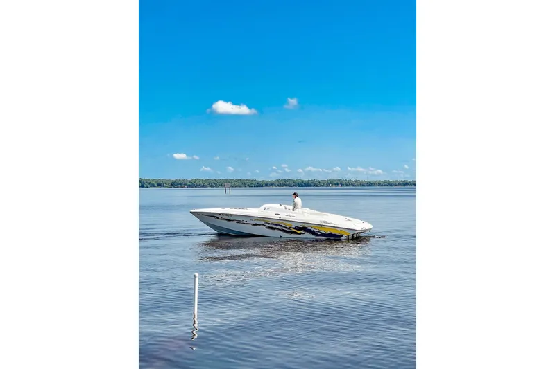 Slide: The Image of 2001 Powerquest 280 Silencer boat cruising on a calm lake under a clear blue sky. - 4
