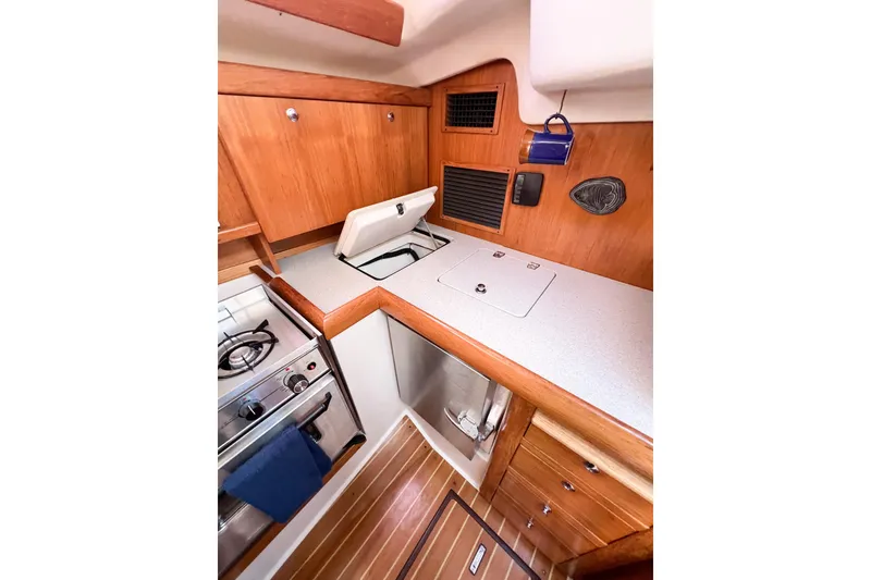 Slide: The Image of 2005 Catalina 350 yacht interior kitchen with stove, wooden cabinets, and countertop. - 22