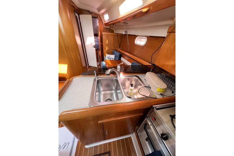 Slide: The Image of 2005 Catalina 350 yacht kitchen with sink, stove, and wooden cabinetry. - 24