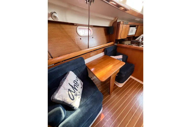 Slide: The Image of Interior of 2005 Catalina 350 sailboat with wooden table and navy seating. - 39